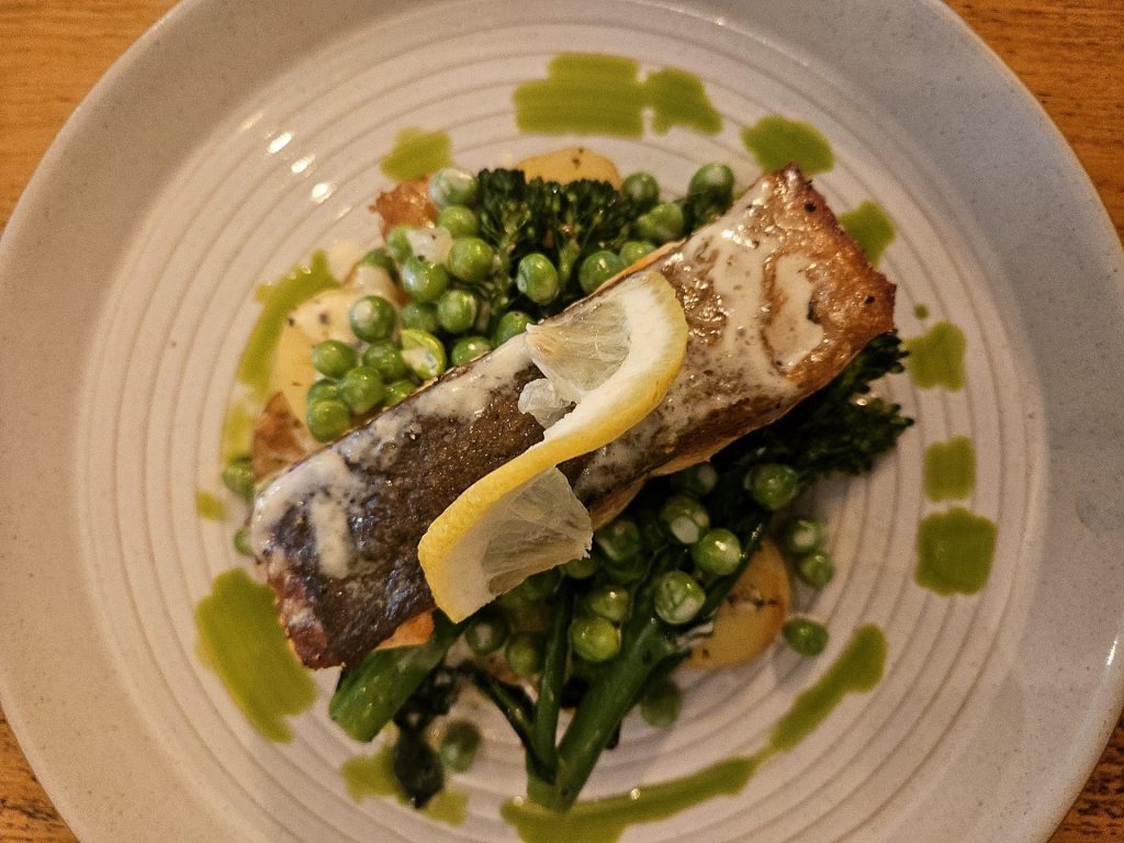 A waiter serves a fresh salad and hors d'oeuvres in a cozy restaurant setting.